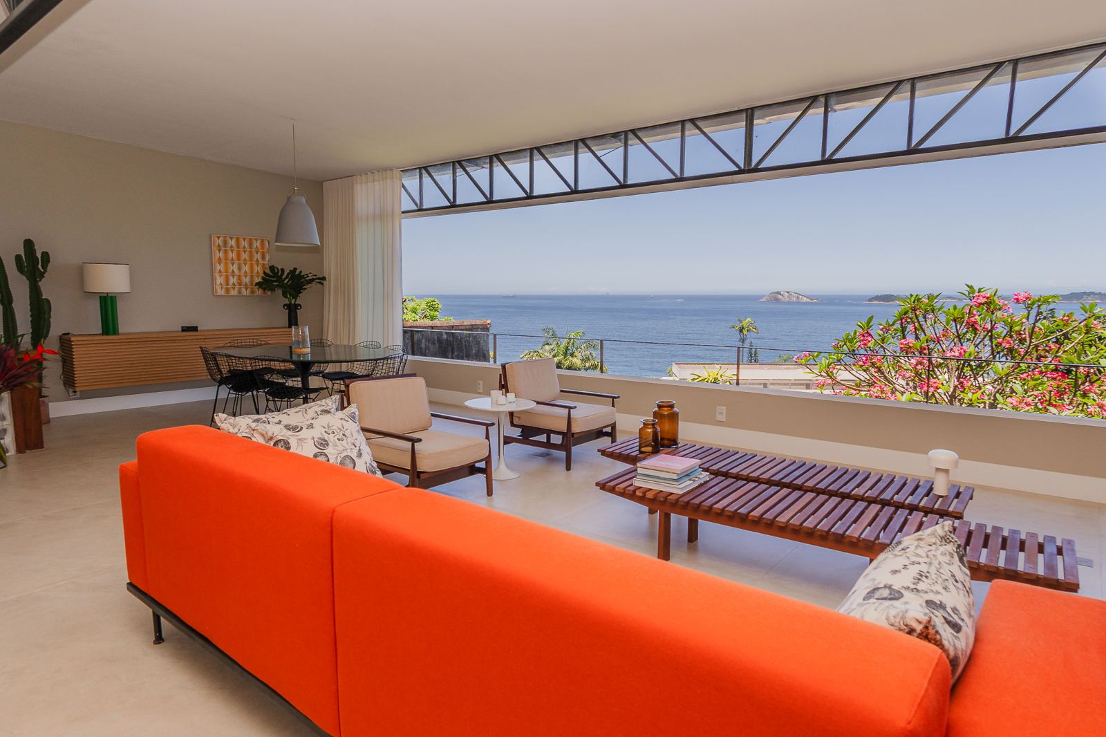Salon de Vila Oriba ouvert sur l'océan, canapé orange et baies vitrées